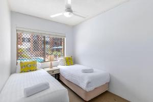 una camera da letto con due letti e una finestra di Relaxed Beachside Escape on the Ground Floor Sandcastles 201 a Coffs Harbour