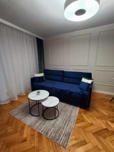 a living room with a blue couch and a table at Apartament Aksamitny in Toruń