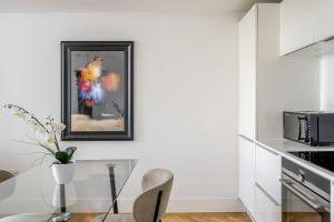 a white kitchen with a glass table and a microwave at Chelmsford Town Centre, Modern 1 Bed Apartment in Chelmsford