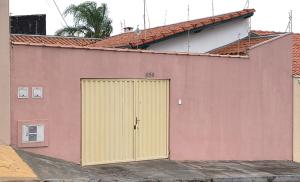 een roze gebouw met een gele garagedeur bij Doce Recanto da re in Franca