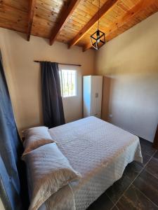 een slaapkamer met een bed in een kamer met houten plafonds bij Complejo Altavista in La Falda