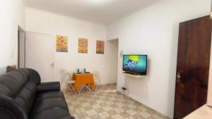 een woonkamer met een bank en een tv aan de muur bij Doce Recanto da re in Franca