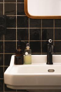 MontrevaultMaison d'hôtes La bien-Aimée的浴室水槽配有2瓶肥皂和镜子