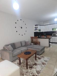 Una sala de estar con un sofá y un reloj en la pared. en Apartamente Noel Vlore, en Vlorë
