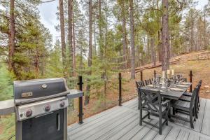 einen Grill und einen Tisch auf einer Terrasse mit einem Tisch und Stühlen in der Unterkunft Mtn-View Cabin with Game Room and Deck in Flagstaff in Mountainaire