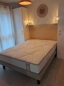 een bed in een kamer met een wit matras bij Le Patio du bourg - Studio entre lac et océan in Biscarrosse