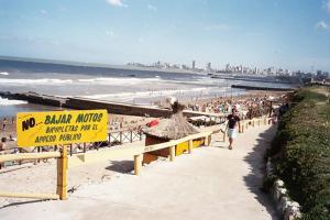 马德普拉塔Tu Alojamiento en Mar del Plata的海滩上竖着一块黄色标志牌，聚集着一群人。