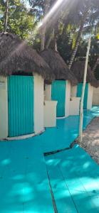 a row of beach huts with blue water and palm trees at Kulu Tubohostel Bacalar in Bacalar
