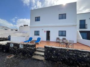 ein weißes Haus mit blauen Stühlen davor in der Unterkunft casa el lajiar in Orzola