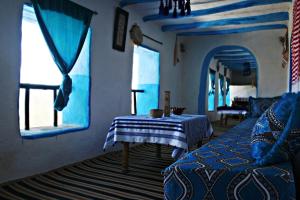 a blue room with a bed and a table and windows at Dar Nefzi in Ouazzane