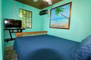 大玉米岛Hospedaje Rosa Del Mar & Sweets Cafe的卧室里有一张蓝色的床和一台电视