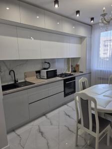 a kitchen with white cabinets and a table with chairs at Аэропорт "EUGEN DOGA"-КИШИНЭУ in Chişinău