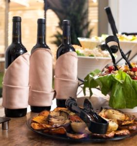 a table with two bottles of wine and a plate of food at Aristocrat Hotel Haredi in Bnei Brak
