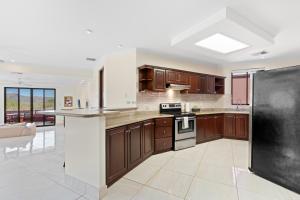 uma cozinha com armários de madeira e um frigorífico preto em Recently Renovated Luxury Condo with Resort-Style Beach Club Access and Ocean Views em Playa Conchal