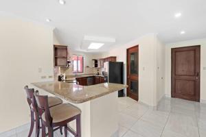 uma cozinha com um balcão com cadeiras e um frigorífico em Recently Renovated Luxury Condo with Resort-Style Beach Club Access and Ocean Views em Playa Conchal mais 24 fotografias