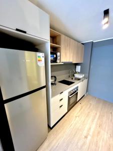 a kitchen with a stainless steel refrigerator and wooden floors at Diseño y conectividad, tu espacio en Santiago in El Cerrillo +8 photos
