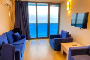 een woonkamer met blauwe meubels en grote ramen bij Superior Aparthotel in ORBI city in Batoemi +31 foto's
