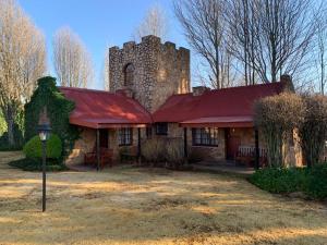 an old stone house with a red roof and a tower at Critchley Hackle - Tower rooms in Dullstroom