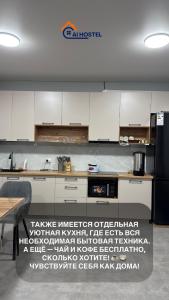 eine Küche mit weißen Schränken und einem schwarzen Kühlschrank in der Unterkunft AI Hostel in Bischkek