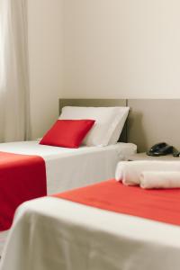 due letti con cuscini rossi uno accanto all'altro di Lagoa Flat Hotel a Lagoa da Prata