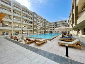 a swimming pool in a building with benches and tables at Alhambra Avenue in Hurghada