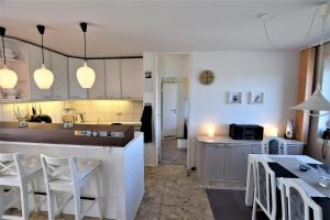 eine Küche mit weißen Schränken und einem Tisch und Stühlen in der Unterkunft Hohes Ufer Mare Nostrum in Hohwacht + 20 Fotos