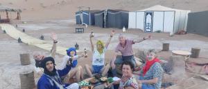 a group of people posing for a picture in the sand at Mhamid appartement in Mhamid +3 photos