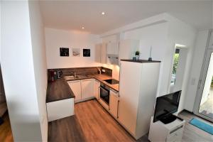 eine kleine Küche mit weißen Schränken und einem Fernseher in der Unterkunft Hohes Ufer Sandburg in Hohwacht + 15 Fotos