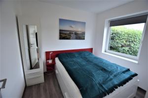 ein weißes Schlafzimmer mit einem Bett und einem Fenster in der Unterkunft Hohes Ufer Sandburg in Hohwacht