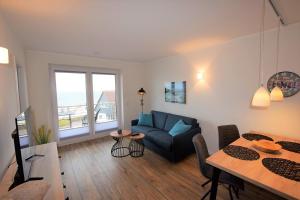 a living room with a blue couch and a table at Meeresblick "Seepferdchen" Haus 3 WE 42 in Hohwacht