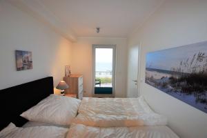 a bedroom with a bed and a large window at Meeresblick "Seepferdchen" Haus 3 WE 42 in Hohwacht
