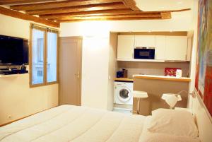 een slaapkamer met een wit bed en een keuken bij Studio Aboukir in Parijs