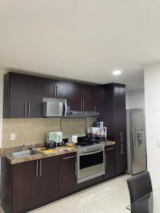 Una cocina con gabinetes de madera y electrodomésticos de acero inoxidable. en Loft ideal para viajes de trabajo cerca del Poliforum, en León