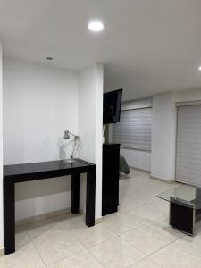 sala de estar con escritorio negro y TV en Loft ideal para viajes de trabajo cerca del Poliforum, en León