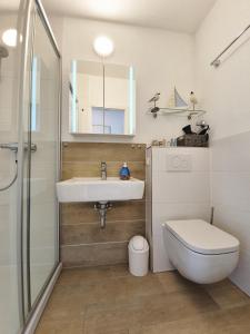 un bagno con lavandino, WC e specchio di Vier Jahreszeiten Haus 2 Whg 27 a Grossenbrode