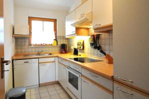 una cucina con mobili bianchi, un lavandino e una finestra di Ferienpark Freesenbruch Wohnung 2 4 - Familientraum a Zingst Altre 33 foto