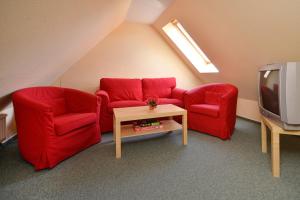 a living room with two red chairs and a tv at Ferienpark Freesenbruch Wohnung 1 6 - Freesenblick in Zingst