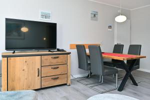 a dining room with a table with chairs and a flat screen tv at Ferienpark Freesenbruch Wohnung 4 3 - Inseltreff in Zingst