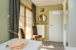 a bedroom with a bed and a mirror and a chair at Ferienpark Freesenbruch Wohnung 4 3 - Inseltreff in Zingst +31 photos