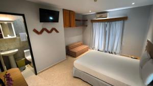 a bedroom with a white bed and a bathroom at Hotel Parguito in La Sabana