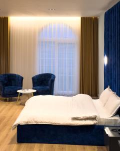 a bedroom with a bed and two chairs and a window at Leo Hotel in Kukës