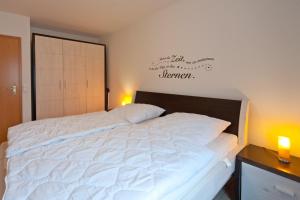 un grande letto bianco in una camera da letto con due luci di Ferienpark Freesenbruch Wohnung 4 2 - Ostseeperle a Zingst Altre 24 foto