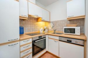 a kitchen with white cabinets and a microwave at Ferienpark Freesenbruch Wohnung 3 5 - Muschelsucher in Zingst