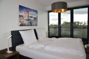 een slaapkamer met een wit bed en een groot raam bij Logierhaus Friedrich WE 24 - "Sandläufer" in Zingst