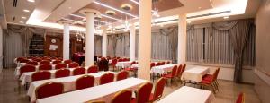 a room with white tables and red chairs at Aristocrat Hotel Haredi in Bnei Brak