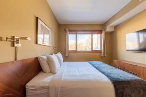 a bedroom with a large bed and a window at El Paraiso - Luxury Downtown Penthouse in Canmore