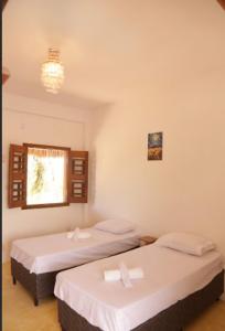 zwei Einzelbetten in einem Zimmer mit Fenster in der Unterkunft Casa andrea in Guriú