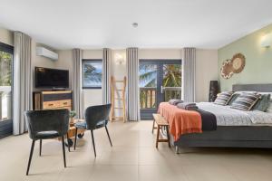 a bedroom with a bed and chairs and a television at Oasis guesthouse, Boutique Style Hotel in Kralendijk