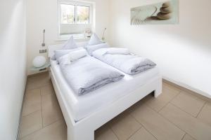 una cama blanca con sábanas y almohadas blancas en SeaSide, en Norderney