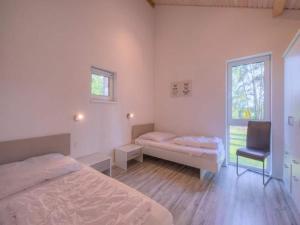 a bedroom with two beds and a chair and a window at XXL Familienferienhaus in Granzow